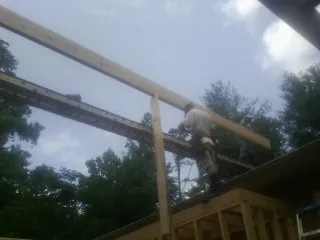 Carpenter setting a ridge beam over a new addition frame — Ice Dam Removal by Roofing Brothers in Pineville