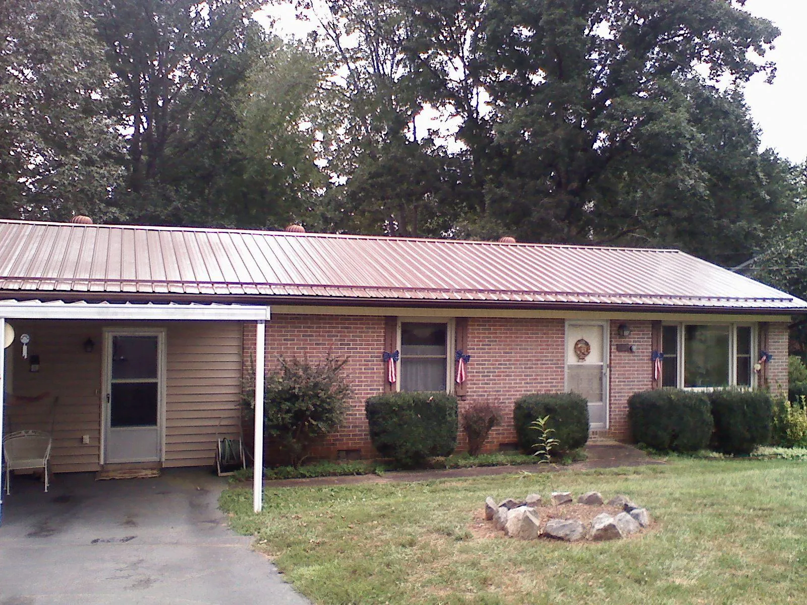 Bronze metal roof and carport on a brick ranch home — Roof Repair work by our crew in Pineville